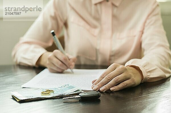 Großes Konzept der Scheidung  Ende einer Beziehung  junge Frau  die eine Scheidungsvereinbarung unterzeichnet. Geld  Autoschlüssel auf dem Tisch