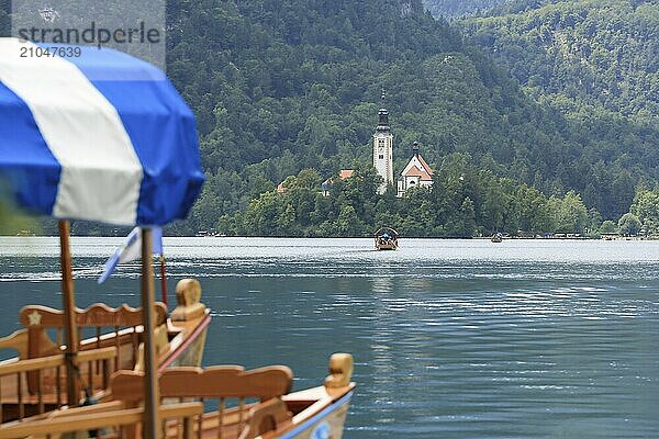 Bleder See mit traditionellem Boot. Schöner Bergsee im Sommer mit kleiner Kirche auf einer Insel mit Schloss auf einer Klippe und Alpen im Hintergrund