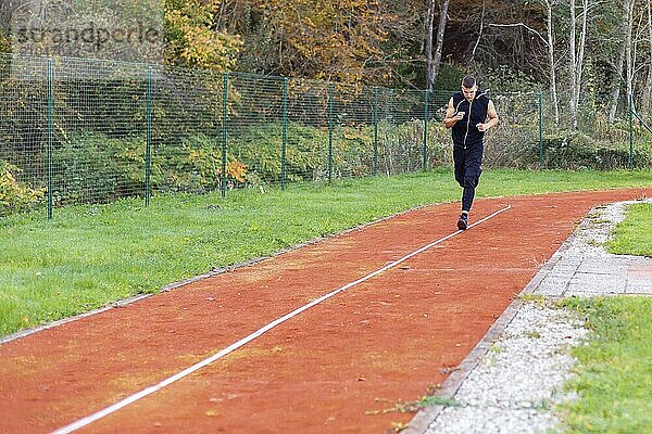 Junger Mann joggt morgens im Freien auf der Laufstrecke