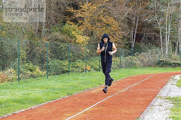 Junger Mann joggt morgens im Freien auf der Laufstrecke