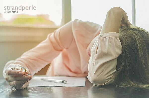 Großartiges Konzept der Scheidung  Ende einer Beziehung  traurige junge Frau  die eine Scheidungsvereinbarung unterzeichnet  mit den Händen im Gesicht