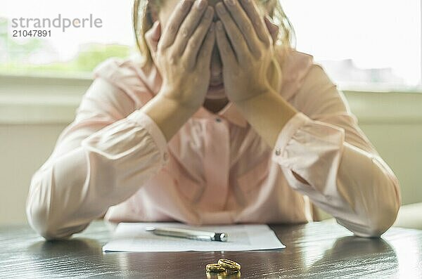 Großartiges Konzept der Scheidung  Ende einer Beziehung  traurige junge Frau  die eine Scheidungsvereinbarung unterzeichnet  mit den Händen im Gesicht