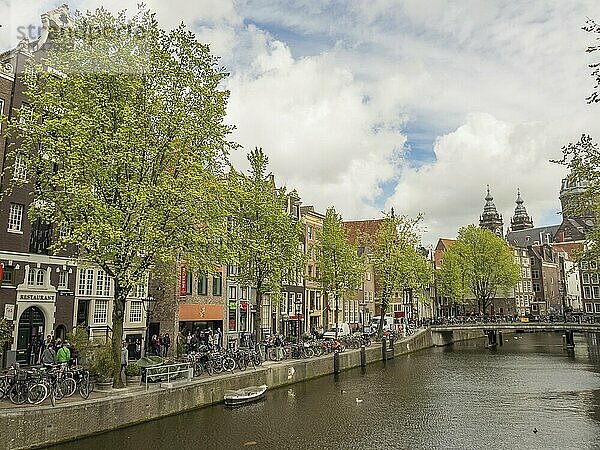 Heitere Straßenansicht mit einem Kanal  Brücke und klassischen Gebäuden  umgeben von grünen Bäumen  amsterdam  niederlande