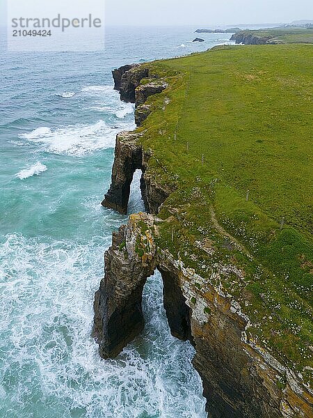 Steilgeklüftete Küstenlinie mit charakteristischen Felsbögen und donnernden Wellen  die gegen die Felsen schlagen  Luftaufnahme  Praia das Catedrais  Playa de las Catedrales  Strand der Kathedrale  As Catedrais Strand  Kantabrisches Meer  Ribadeo  Galicien  Galizien  Spanien  Europa