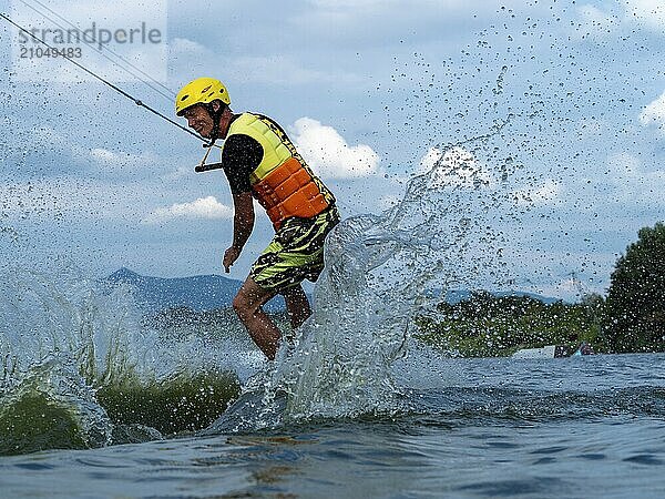 Mann bei Sprung mit Wakeboard  Wassersport  Wasserski und Wakepark