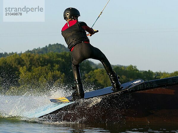 Junger Mann mit Wakeboard auf Hindernis  Wassersport  Wasserski im Wakepark