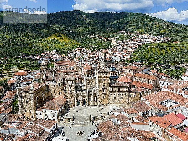 Luftaufnahme eines alten Klosters mit roten Dächern  umliegenden Bergen und grünen Hügeln  dargestellt in einer historischen Umgebung in Spanien  Luftaufnahme  Wallfahrtskirche und Kloster  Real Monasterio de Nuestra Señora de Guadalupe  Guadalupe  Provinz Cáceres  Caceres  Extremadura  Spanien  Europa