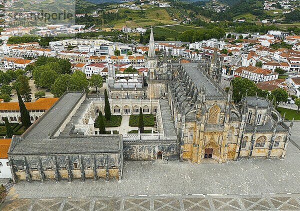 Luftaufnahme eines gotischen Klosters mit einem zentralen Innenhof  umgeben von verschiedenen Gebäuden und grünen Hügeln in einer historischen Stadt  Luftaufnahme  Kloster  Mosteiro de Santa Maria da Vitória  'unvollendete Kapellen'  UNESCO-Welterbe  Batalha  Leiria  Estremadura  Portugal  Europa