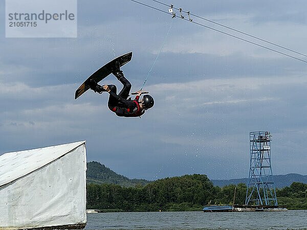 Mann bei Sprung mit Wakeboard über Hindernis  Salto  Wassersport  Wasserski und Wakepark  Stráž pod Ralskem  Tschechin