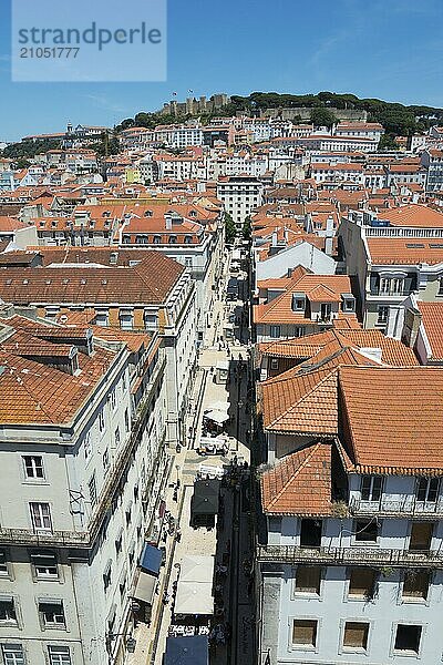 Luftaufnahme einer engen Gasse mit hohen Gebäuden und roten Ziegeldächern in einer sonnigen Stadt  Blick auf Burg  Aussichtspunkt  Miraduoro Terracos Do Carmo  Blick auf Castelo de São Jorge  Burg Saint George  Altstadt  Lissabon  Lisboa  Portugal  Europa