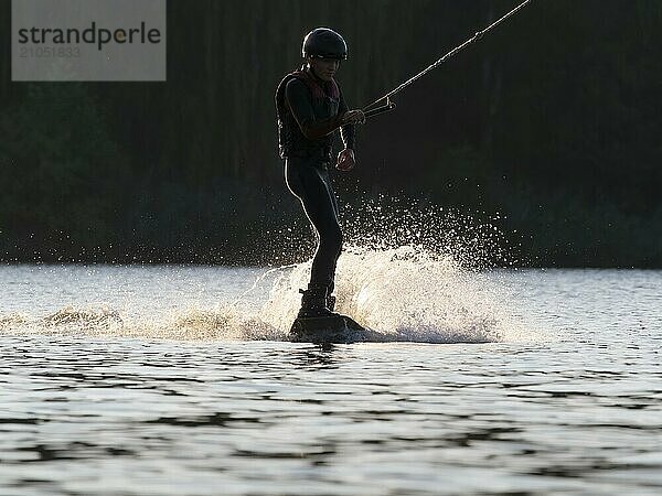 Junger Mann mit Wakeboard im See  ruhige Fahrt  Wassersport  Wasserski im Wakepark