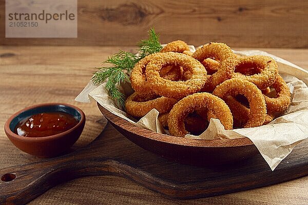 Frittierte Zwiebelringe  Vorspeise  mit Tomatensauce  auf einem Holztisch  ohne Menschen  Lieblingsgericht