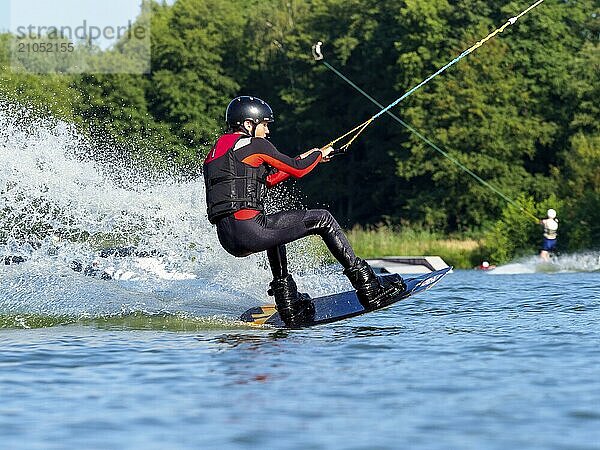 Junger Mann bei sportlicher Fahrt mit Wakeboard im See  Wassersport  Wasserski im Wakepark  Stráž pod Ralskem  Tschechin