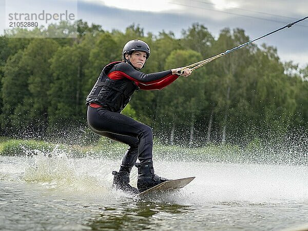 Junger Mann  athletisch  fährt rasant mit Wakeboard  Wassersport  Wasserski und Wakepark  Stráž pod Ralskem  Tschechin