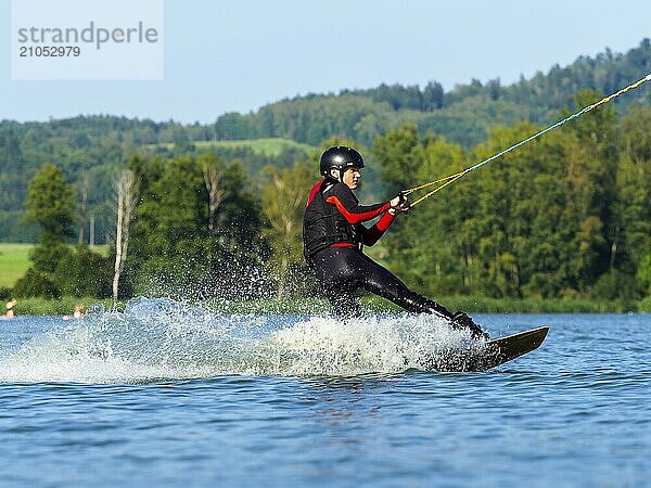 Junger Mann bei sportlicher Fahrt mit Wakeboard im See  Wassersport  Wasserski im Wakepark  Stráž pod Ralskem  Tschechin