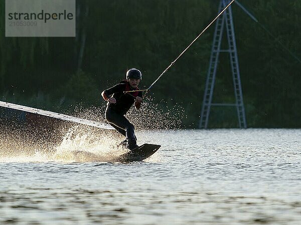 Junger Mann mit Wakeboard im See  Wassersport  Wasserski im Wakepark