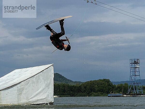 Mann bei Sprung mit Wakeboard über Hindernis  Salto  Wassersport  Wasserski und Wakepark  Stráž pod Ralskem  Tschechin