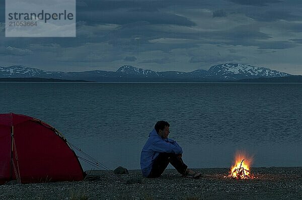 Mann sitzt am Lagerfeuer neben seinem Biwak am See Virihaure  Padjelanta Nationalpark  Welterbe Laponia  Lappland  Schweden  Lappland  Schweden  Europa