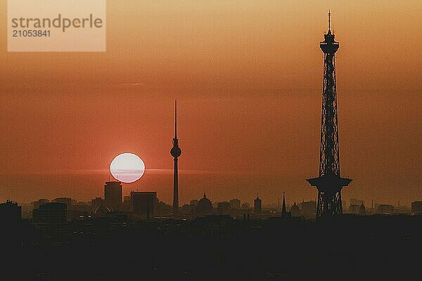 Der Sonnenaufgang zeichnet sich ab hinter der Stadtsilhouette mit dem Fernsehturm und dem Funkturm in Berlin  04.09.2024