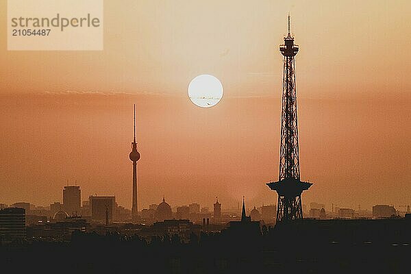 Der Sonnenaufgang zeichnet sich ab hinter der Stadtsilhouette mit dem Fernsehturm und dem Funkturm in Berlin  04.09.2024