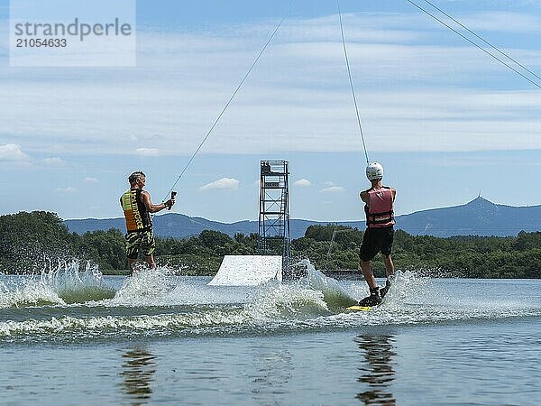 Wassersport mit Wakeboard  zwei Männer fahren nebeneinander im See  Kamera in der Hand  Wasserski und Sommerurlaub  Stráž pod Ralskem  Tschechin