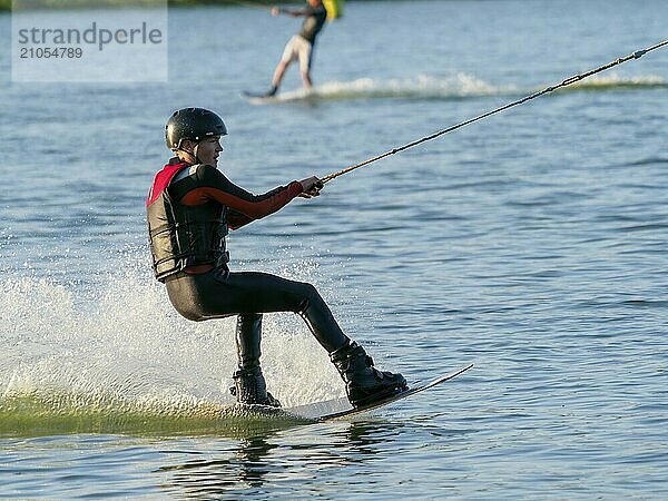 Junger Mann mit Wakeboard im See  Wassersport  Wasserski und Wakepark