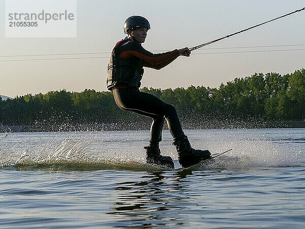 Junger Mann mit Wakeboard im See  Wassersport  Wasserski im Wakepark