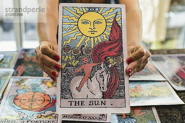 Nahaufnahme der riesigen Tarotkarte Die Sonne in der Hand des Tarotlesers