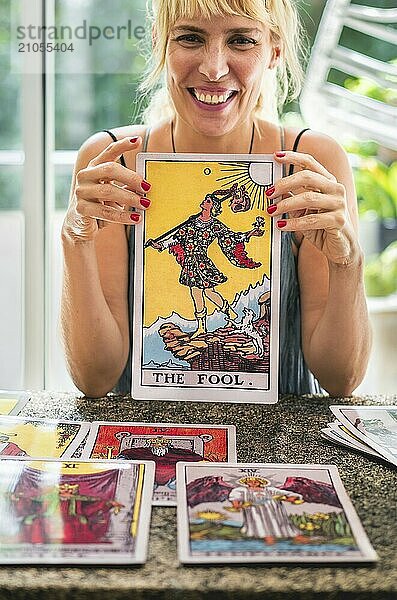 Tarot Leser hält lachend die riesige Tarotkarte Der Narr in der Hand