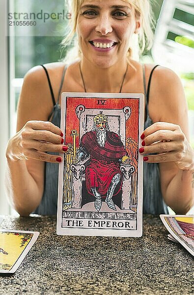 Fröhlicher Tarotleser  der die riesige Tarotkarte Der Kaiser zeigt