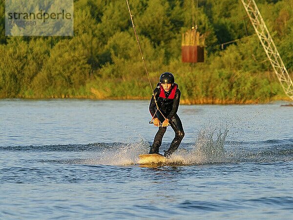 Junger Mann mit Wakeboard im See  Wassersport  Wasserski und Wakepark