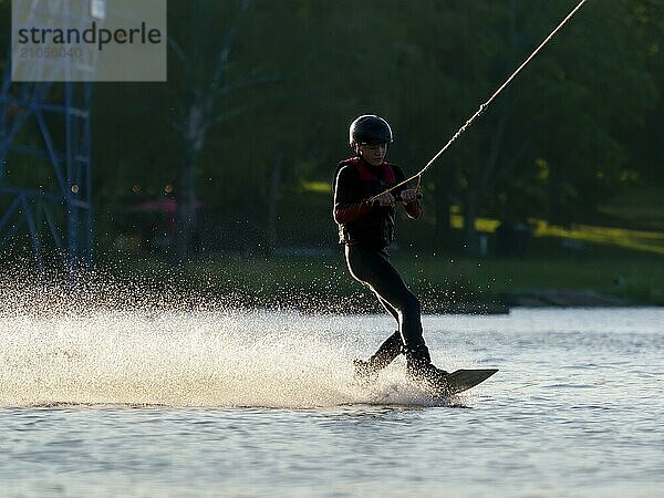 Junger Mann mit Wakeboard im See  Wassersport  Wasserski im Wakepark