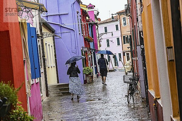 Stadtansicht von Burano mit bunt bemalten Häusern und Kanälen. Regenwetter  die Menschen haben Schirme bei sich. Burano  Venedig  Venezien  Italien  Europa