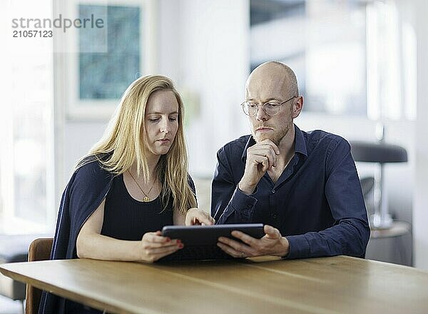 Symbolfoto. Eine Frau und ein Mann sitzen zusammen an einem Tisch mit einem Tablet und unterhalten sich. Berlin  13.08.2024