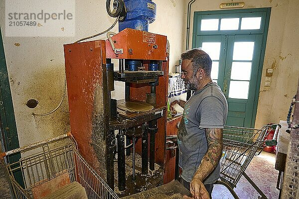 Ein Mann bedient eine Ziegelpresse in einer Werkstatt  Ziegel und Metallmaschine sichtbar  Ziegelbrennerei Patmos Cotto  Traditionelle Ziegelherstellung  Kampos  Patmos  Dodekanes  Griechische Inseln  Griechenland  Europa