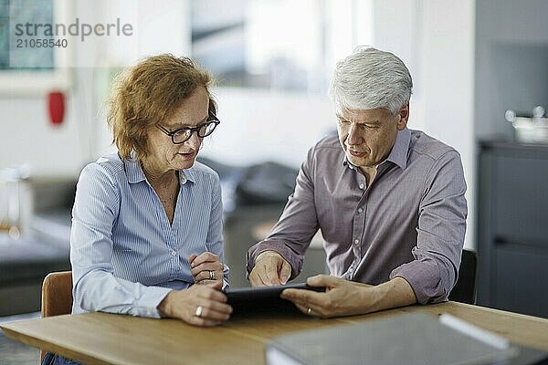 Symbolfoto. Eine Frau und ein Mann sitzen zusammen an einem Tisch mit einem Tablet und unterhalten sich. Berlin  13.08.2024