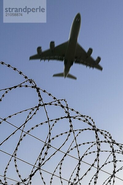 Symbolbild  Abschiebeflüge von illegalen und straffälligen Migranten  Bild eines fliegenden Flugzeugs über Stacheldraht im Sonnenuntergang  symbolisiert Freiheit und Sicherheit  Sicherheitszaun  Baden-Württemberg  Deutschland  Europa