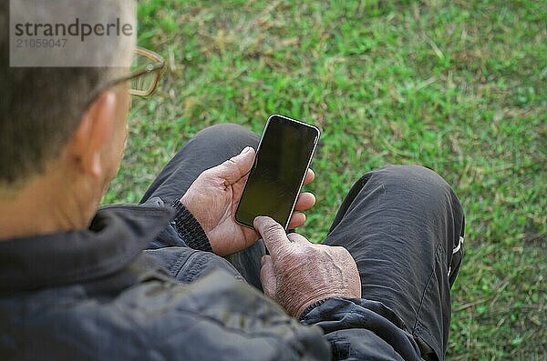 Nahaufnahme des faltigen Fingers eines Mannes  der ein Mobiltelefon berührt