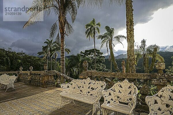 Blick auf eine Terrasse in warmem Licht mit Palmen und einer großen grauen Wolke im Hintergrund  Caraca Natural Park  Minas Gerais  Brasilien  Südamerika