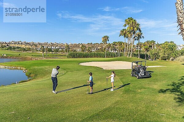 Totale Weitsicht eines männlichen Golflehrers  der zwei Kindern auf einem Golfplatz Golf beibringt