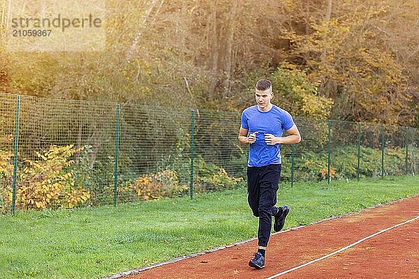 Junger Mann joggt morgens im Freien auf der Laufstrecke