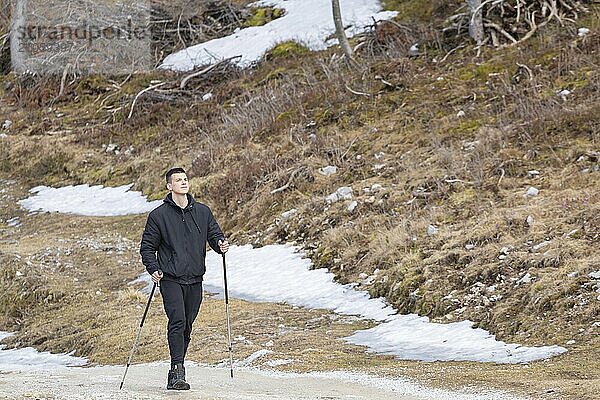 Lässiger und aktiver gesunder Mann beim Wandern in den alpinen Bergen mit Trekkingstöcken