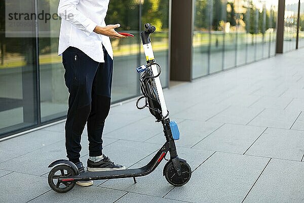 Junger und lässiger Geschäftsmann fährt Elektroroller in der Stadt