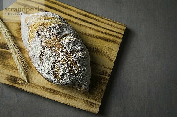 Schönes Sauerteigbrot auf grauem Hintergrund mit getrockneter Weizenblüte