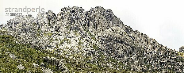 Landschaftlich zerklüftete Granitberge der Serra da Mantiqueira (Mantiqueira Gebirgskette) mit grasbewachsenen Teilen vor hellem Hintergrund  oberes Itatiaia  Brasilien  Südamerika