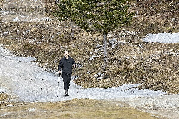 Lässiger und aktiver gesunder Mann beim Wandern in den alpinen Bergen mit Trekkingstöcken