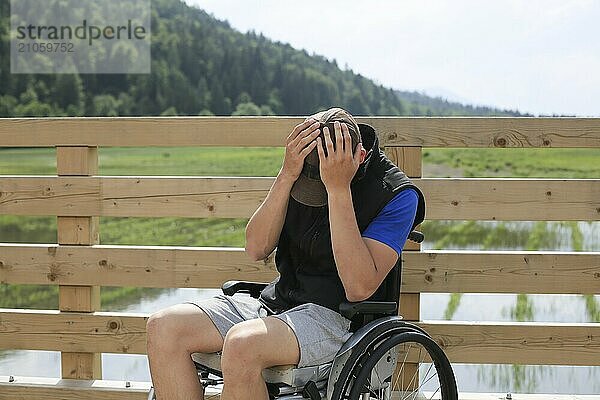 Behinderter junger Mann im Rollstuhl in der Natur  deprimiert  einsam und traurig