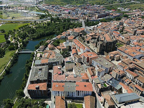 Luftaufnahme einer Stadt mit roten Ziegeldächern  Fluss  Brücke und grünen Bäumen an einem sonnigen Tag  Luftaufnahme  Plasencia  Fluss Jerte  Cáceres  Caceres  Extremadura  Spanien  Europa