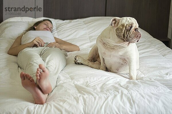 Schöne Frau schläft im Bett mit englischer Bulldogge Welpe. Nur die Füße