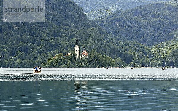 Bleder See mit traditionellem Boot. Schöner Bergsee im Sommer mit kleiner Kirche auf einer Insel mit Schloss auf einer Klippe und Alpen im Hintergrund